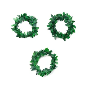 Detailed view of three artificial green leaf napkin rings for elegant table setting.