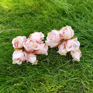 Vista ravvicinata di mazzi di rose artificiali vintage rosa chiaro su erba verde naturale.