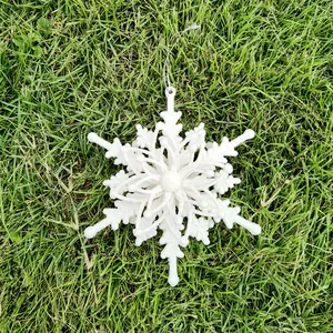 Detail view of a 12cm white glittery 3D snowflake ornament on green grass backdrop.