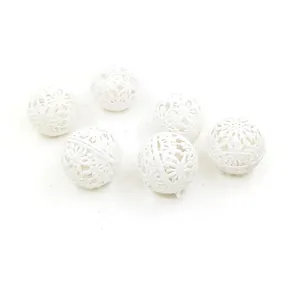 Detailed view of white hollow-out Christmas baubles with glitter texture for tree decor.