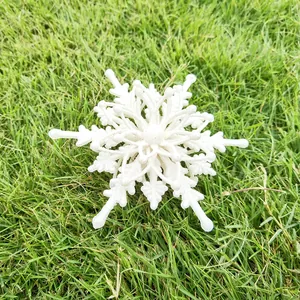 Detailed macro view of a 12cm white 3D glitter snowflake ornament placed on green grass