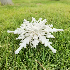 Large white 3D snowflake Christmas ornament displayed on a lush green grass background
