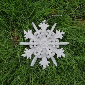 12cm white glitter snowflake ornament for Christmas tree decoration on green grass.