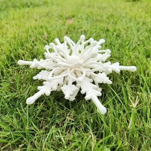 Close-up of 12cm white 3D Christmas snowflake ornament with glitter texture on green grass