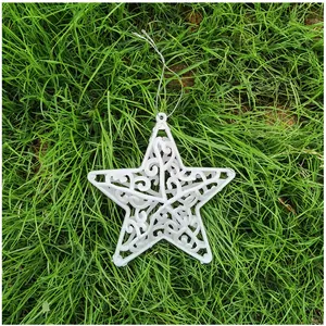 Detailansicht eines weißen, hohlen Glitzerstern-Weihnachtsschmucks auf saftig grünem Gras.