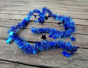 Close-up view of shiny blue metallic tinsel garland with star decorations on wood