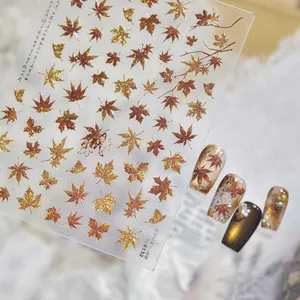 Close-up of vintage red-brown metallic maple leaf nail art stickers with sample nail tips