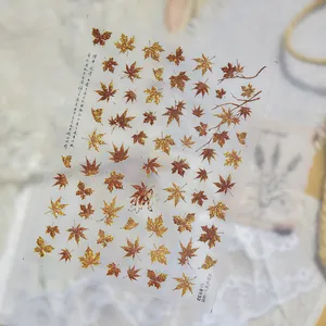 Close-up detail of retro red-brown maple leaf metal nail art stickers for DIY