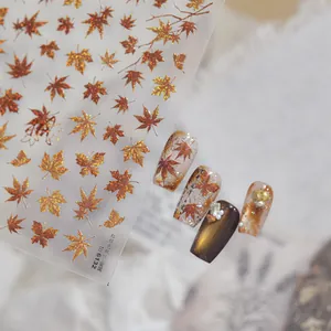 Detail view of metallic red-brown maple leaf nail stickers with decorative nail art