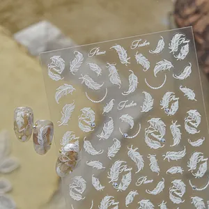 Detailed macro view showing white feather nail art stickers with elegant crystal accents