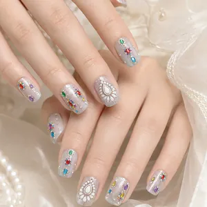 Close-up of luxury nail stickers with colorful gems and glitter finish.