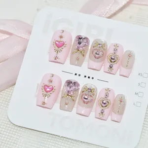 Faux ongles faits main rose avec des gemmes en cœur et des motifs d'étoiles dorées