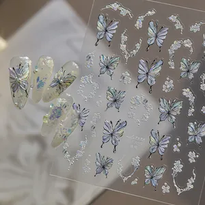 Close-up detail of iridescent holographic butterfly and floral nail art stickers on clear film.