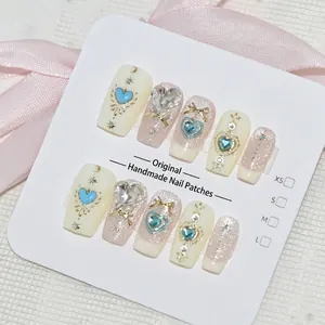 Détail macro de faux ongles de haute qualité faits à la main avec des breloques cœur bleu