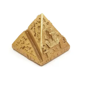 Close-up of golden Egyptian pyramid figurine with pharaoh and hieroglyph carvings