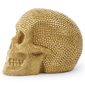 Close-up detail of golden resin skull mask with intricate rhinestone texture for Halloween.