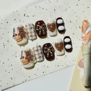 Vista dettagliata di unghie finte fatte a mano con orsetto 3D e design torta di castagne