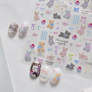 High-detail macro shot of 3D embossed cute cartoon bear and bow nail art stickers.