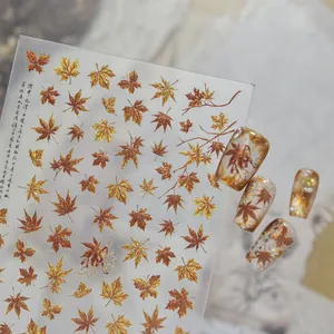 Macro view of vintage gold and bronze maple leaf nail art stickers with 3D effect