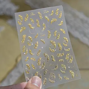 Detail showing golden feather nail art stickers with delicate crystal rhinestones