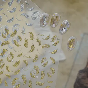 Close-up of gold and silver metallic feather nail art stickers with applied display