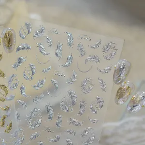 Close-up of metallic silver feather nail art stickers with 3D embossed texture