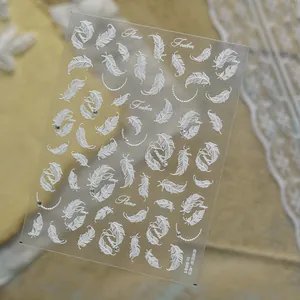 Close-up detail of vintage white feather nail art stickers with small shiny rhinestones