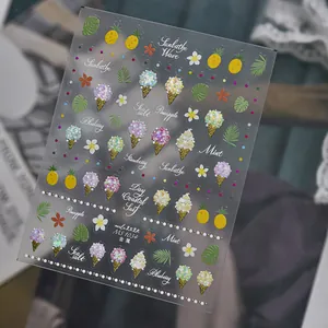 Primer plano de pegatinas metálicas para uñas con motivos de helado, piña y flores.