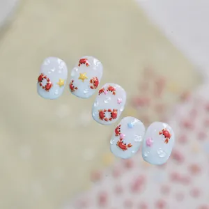 Vue macro détaillée de stickers 3D pour ongles crabe et étoile sur base bleu clair