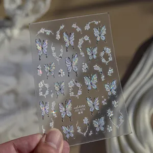 Detail view of holographic butterfly and floral nail art stickers on a transparent sheet