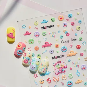 Gros plan d'autocollants 3D pour ongles avec motifs de monstres et visages souriants.