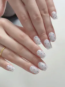 Detailaufnahme handgefertigter Press-on-Nägel mit blauen Punkten auf weißer Basis