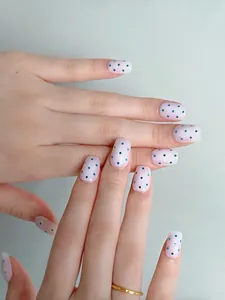 Elegante handgefertigte Kunstnägel mit rosa Litschi-Basis und grünen Punkten am Finger