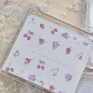 Détail des bijoux d'ongles de luxe en forme de fraise et de raisin dans un étui clair
