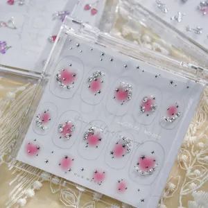 Vue macro de stickers pour ongles rose dégradé avec étoiles et strass en boîte.