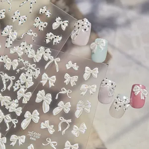 Detalle de pegatinas 3D para uñas con lazos iridiscentes y acabado de brillo de concha