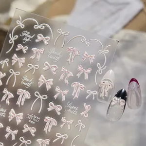 Vista macro de pegatinas 3D para uñas con lazo rosa perlado y acabado de concha brillante