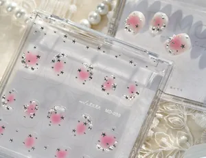 Détail d'autocollants nail art étoilés avec blush rose et strass sur une planche