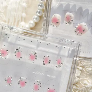 Vue détaillée de décors d'ongles blush rose avec étoiles argentées et strass brillants.
