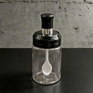 Dettaglio del barattolo di vetro per condimenti con cucchiaio integrato e trasparente.