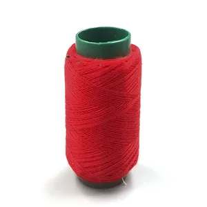 Detailed view of red sewing thread spool with green core, showing neat winding for clothing repair.