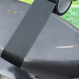 Detailopname van de zwarte lederen reparatietape die een stoelscheur repareert.