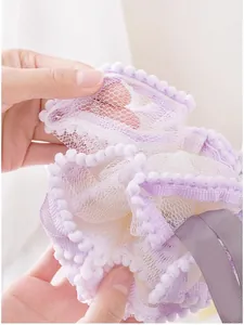 Détail en gros plan d'une éponge de bain en filet violet doux avec bordure pompon et sangle solide.