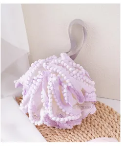 Gros plan détaillé de la grande éponge de bain violette avec bordure pompon et attache.
