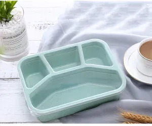Detail view of a light green four-compartment wheat straw bento box on a cozy tabletop.