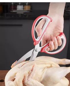 Detailaufnahme einer multifunktionalen Küchenschere mit ergonomischem Griff beim Schneiden.