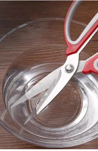 Nahaufnahme der Edelstahl-Küchenschere Klinge und des ergonomischen Griffs in Glasschüssel.