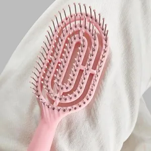 Detailed close-up of a pink curved hair brush with massage beads for easy daily hair styling.