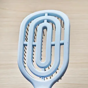 Detail shot of the blue curved vent hair brush, ergonomic hollow design for gentle daily styling.