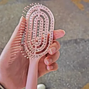 Close-up detail of the pink curved vent hair brush, ergonomic arched design for easy styling.